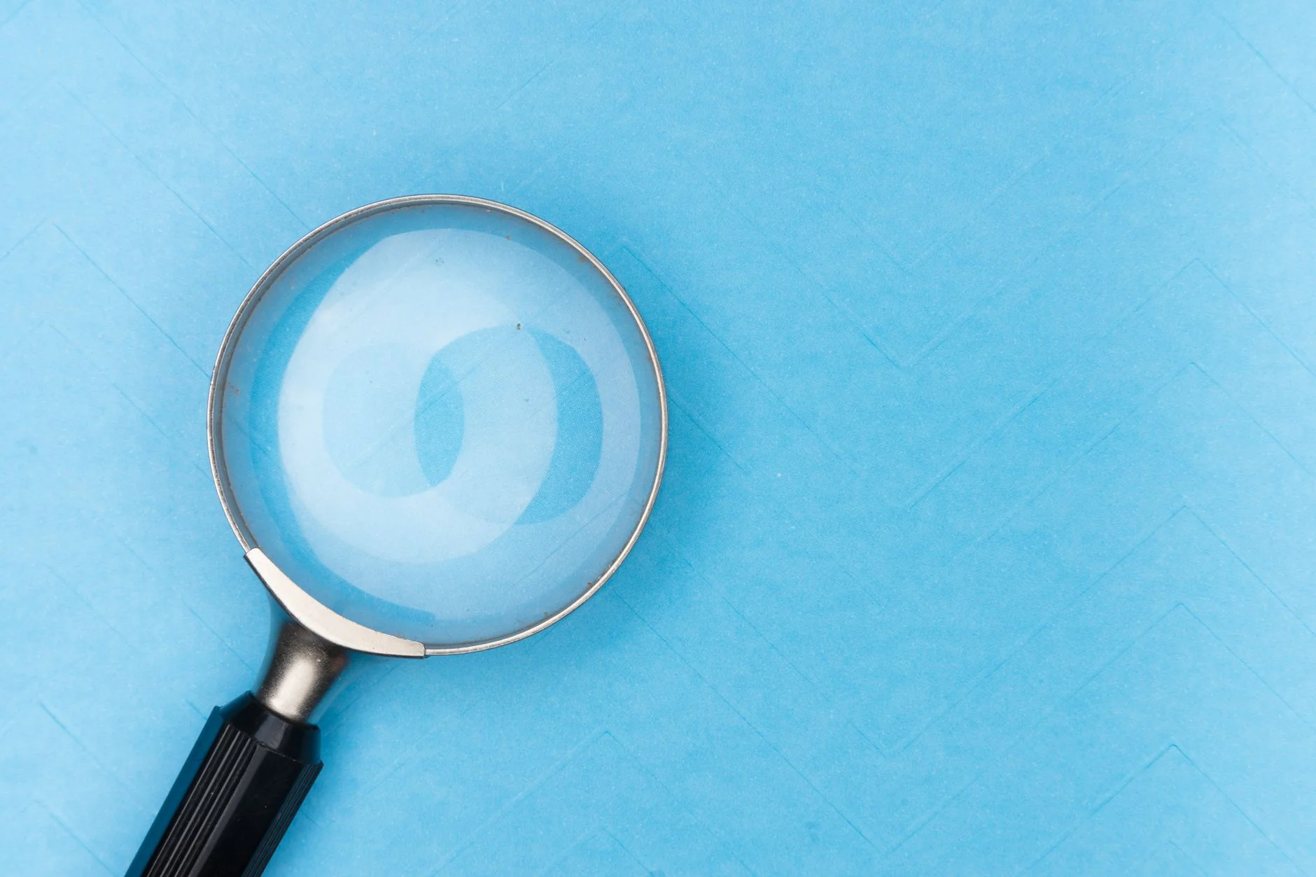 Magnifying glass held over a printed document on a desk, evoking careful diagnosis