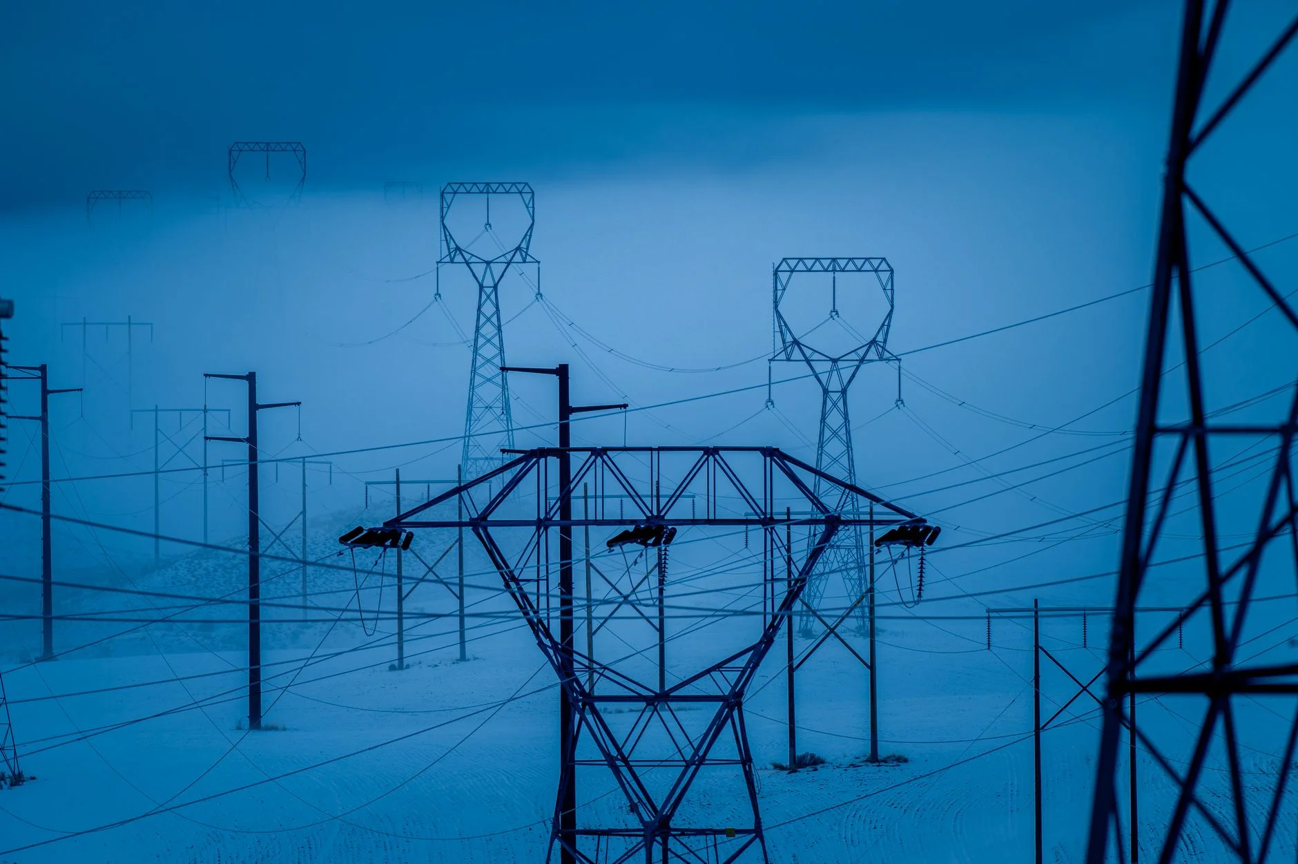 High-voltage power substation wires and transformers under a clear sky, representing automated infrastructure running under load