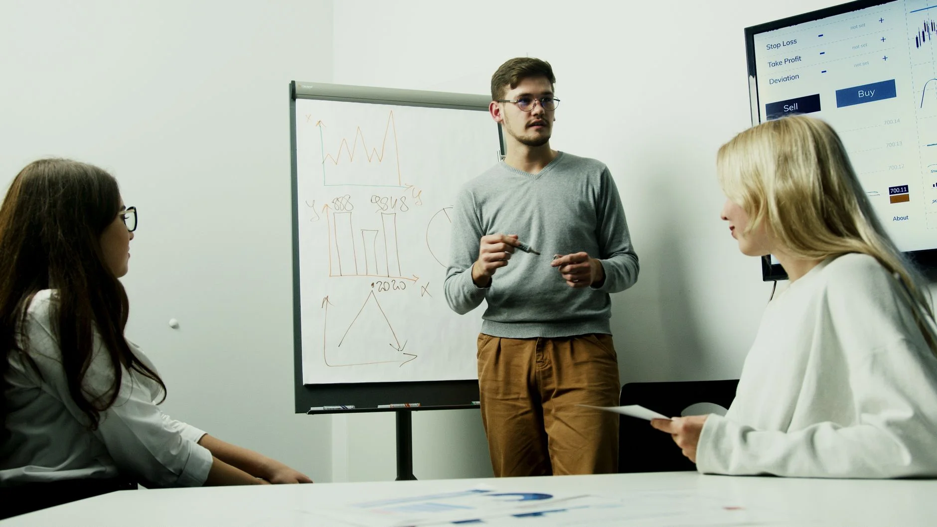 A small team reviewing charts and notes on a whiteboard during a strategy meeting